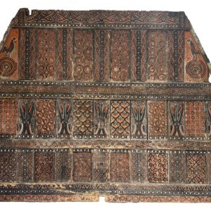 An authentic, intricately hand-carved antique wooden gable panel from a Toraja Tongkonan house in Sulawesi, featuring traditional red, black, and yellow tribal motifs.